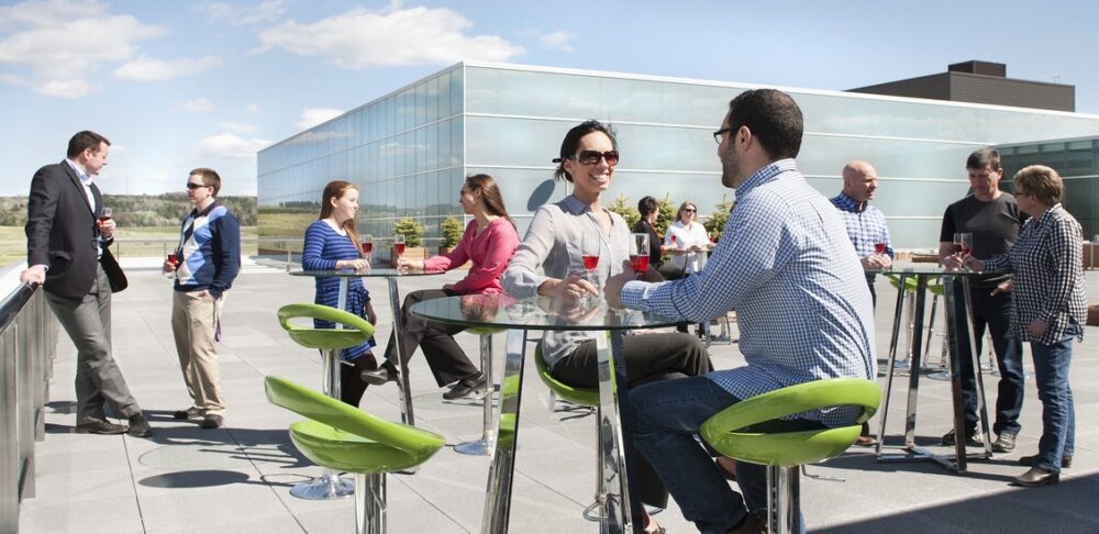 A photo of people talking on a sunny Sports Plex patio.