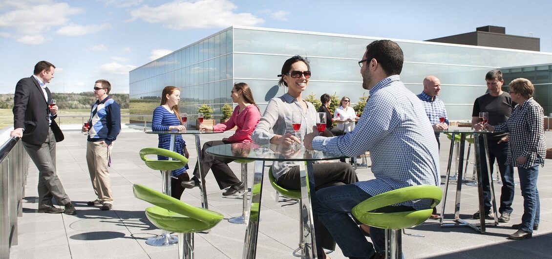 A photo of people talking on a sunny Sports Plex patio.