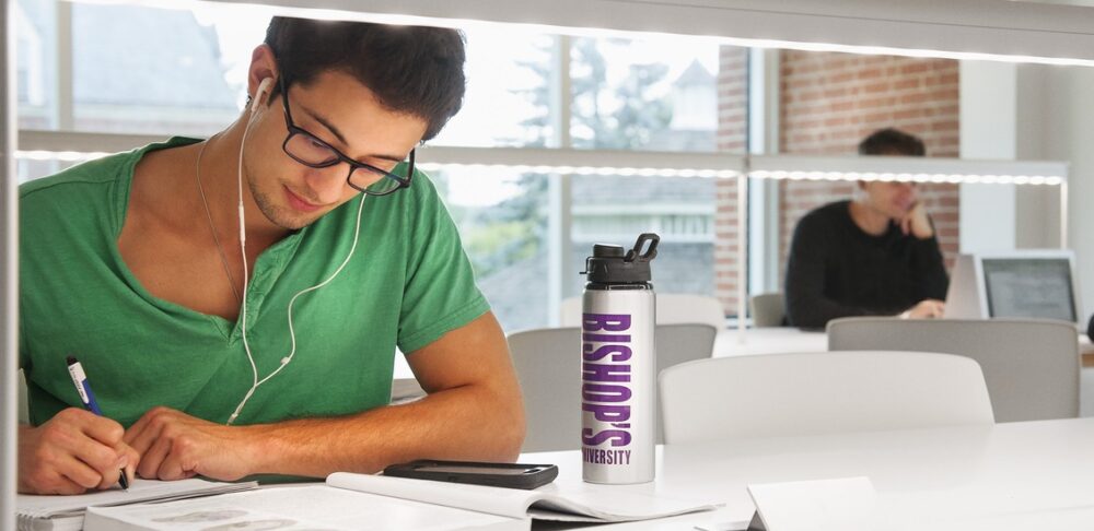 A focus on a man wearing headphones studying in a library.