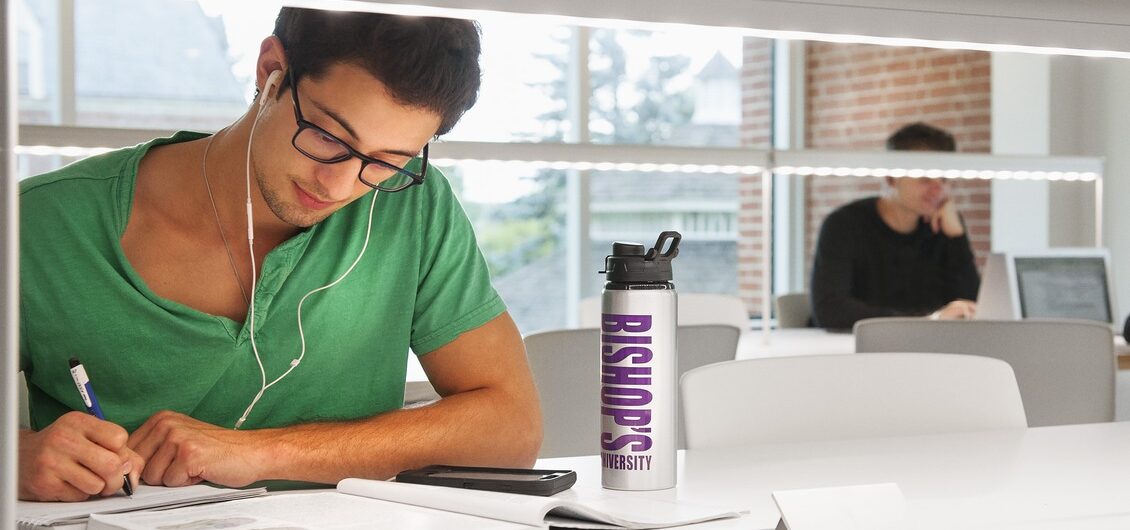 A focus on a man wearing headphones studying in a library.