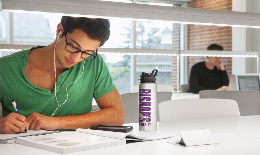 A focus on a man wearing headphones studying in a library.