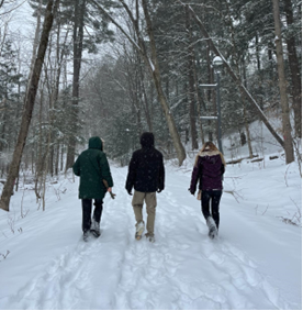 Three people walking on a snowy trail.