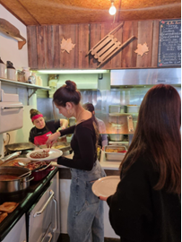 A few people serving themselves at a maple grove buffet. The room is rustic in style.