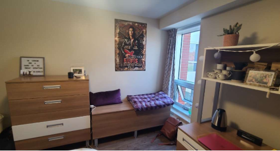 Bishop's residence room, with a window, a dresser, desk and decoration.