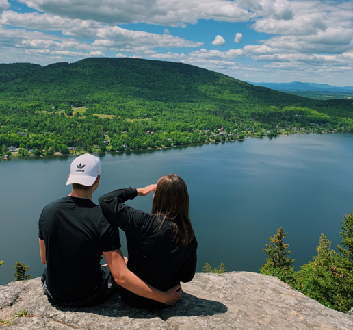 A photo of a young man and woman looking out onto the water below the Mont Pinnacle Trail, one of the best landscapes in our region.