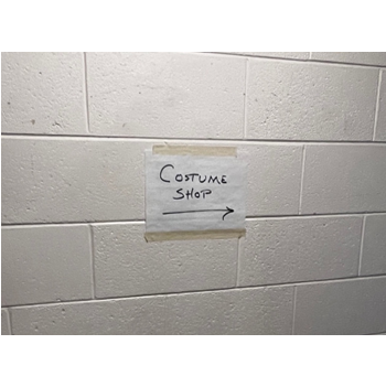 A paper sign reading 'costume shop' with an arrow pointing right.