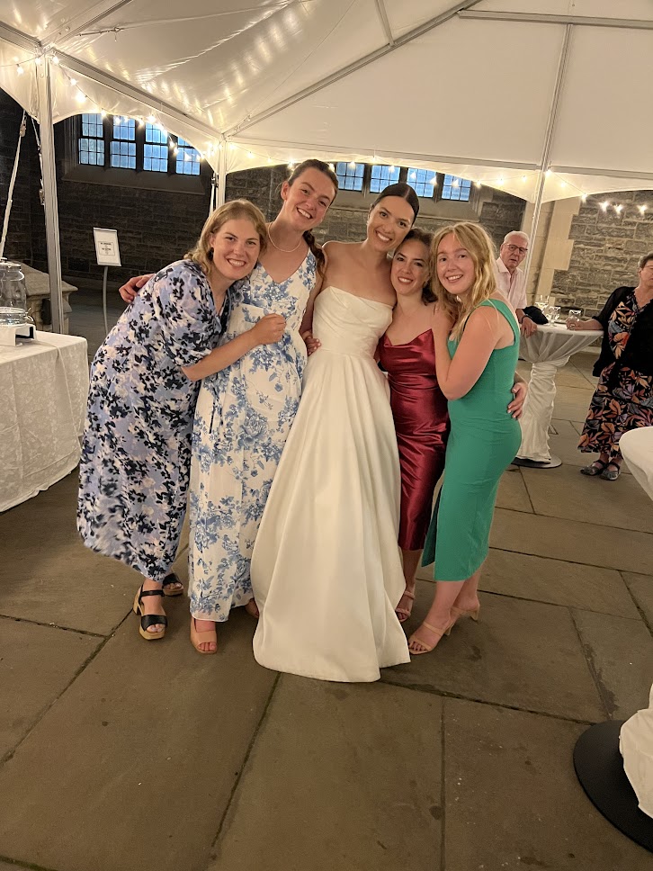 Group of friends at a wedding, posing with the bride.