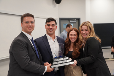 Four people holding a trophy.