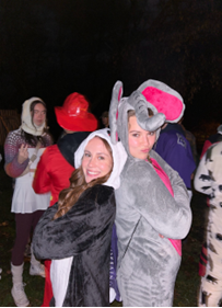 Two girls posing back-to-back, one in a panda onesie, one in an elephant onesie.