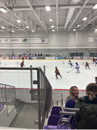 View from the seats at a hockey game with players on the ice.